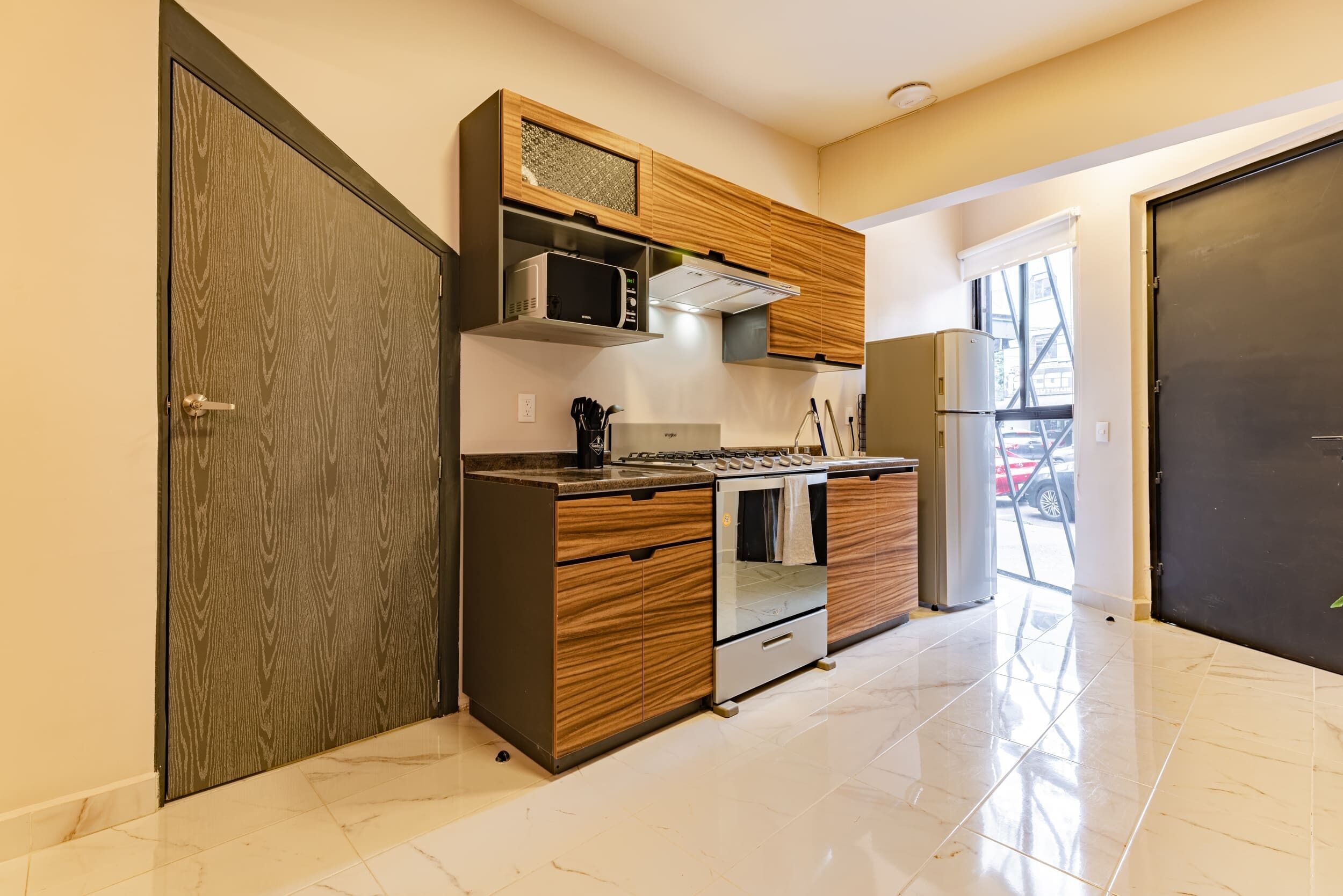 A modern kitchen with wooden cabinetry, a built-in microwave, a stove, and a refrigerator.