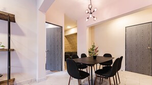 Un espace de salle à manger moderne avec une table ronde, des chaises noires et un lustre.