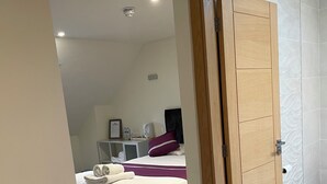 A bedroom with a bed, pillows, a bedside table, and a wall-mounted shelf. - Oakham hotel (Oakham)