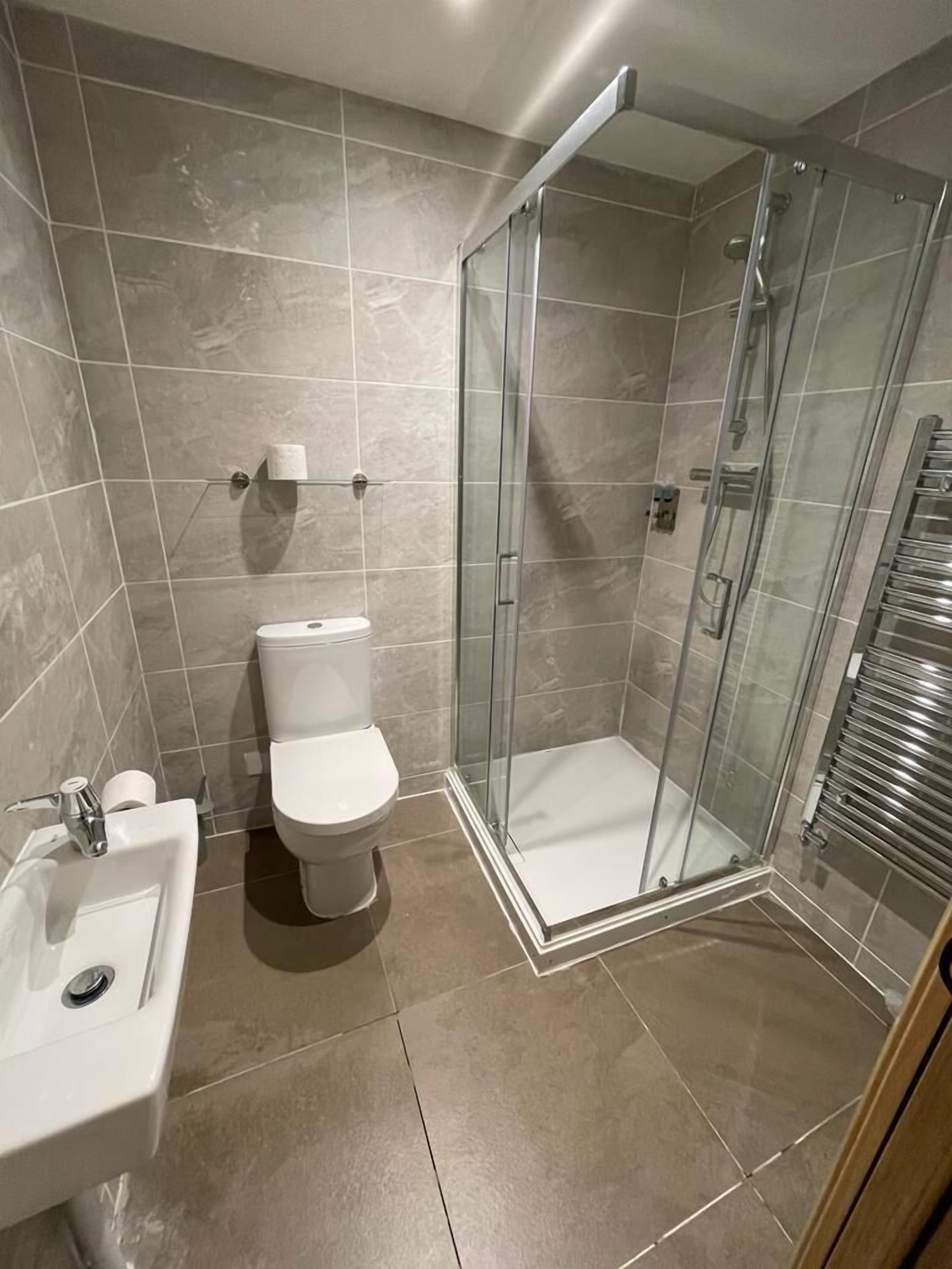 A modern bathroom with a glass-enclosed shower, a toilet, and a sink.