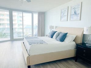 A bedroom with a large bed, two bedside lamps, a nightstand, and a view of a balcony with a railing. - DOWN BY THE BAY! 3RD FLOOR 2 BEDROOM 2 BATH UNIT!! ASK ABOUT DISCOUNTS! (Orange Beach)