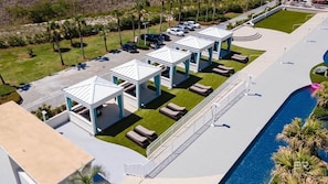 Vue aérienne d’un complexe hôtelier comprenant plusieurs structures blanches en forme de gazebo, une piscine et un parking.