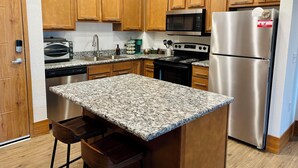 A kitchen with wooden cabinets, a stainless steel refrigerator, a microwave, a stove, and a built-in oven. - 2 bed 2 bath apartment in Castle (Grandville)