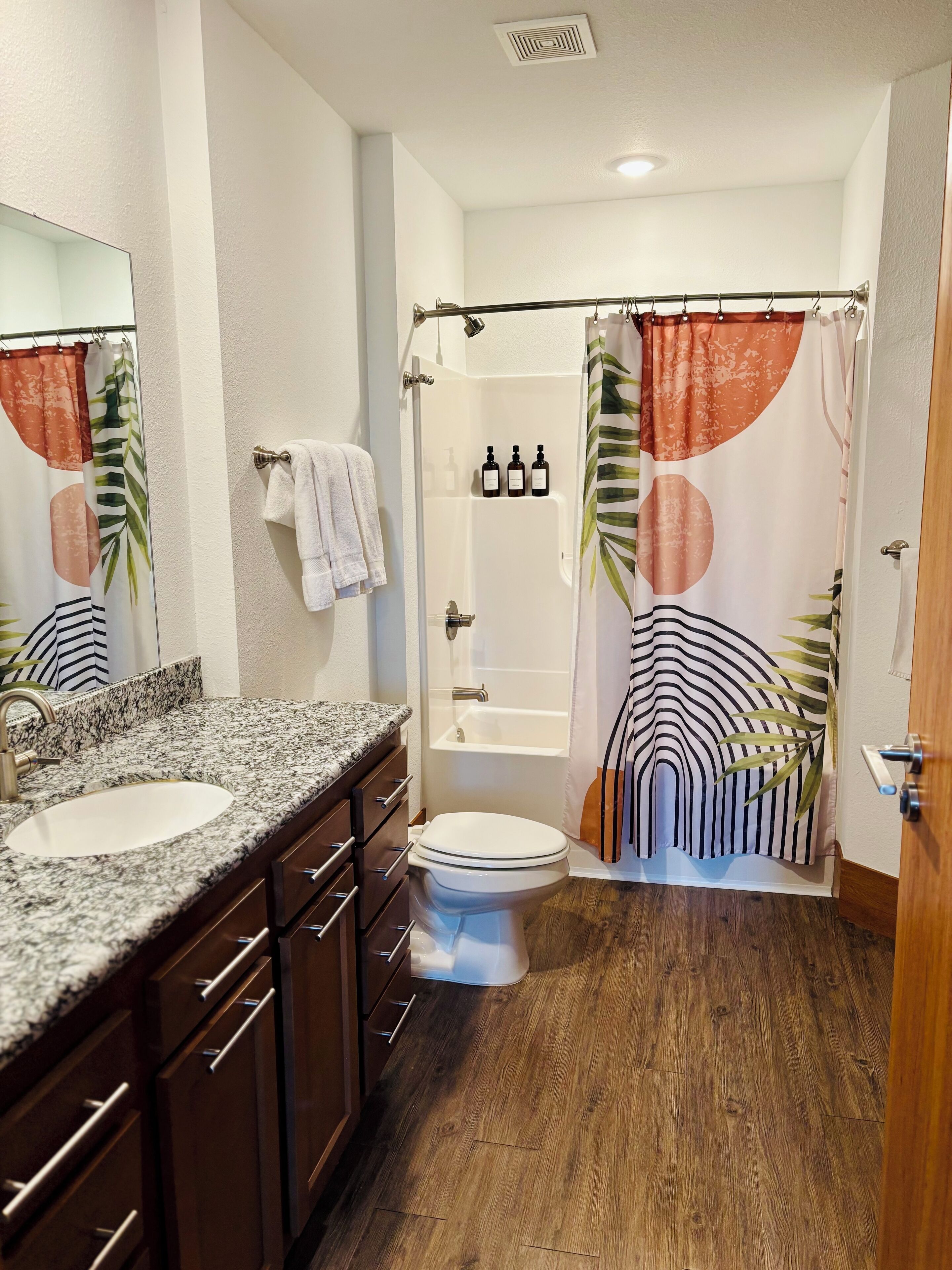 A bathroom with two sinks, a toilet, a shower with a curtain, and a mirror.