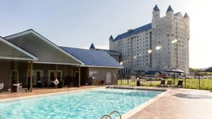 A swimming pool with a covered area and a large building in the background. - 2 bed 2 bath apartment in Castle (Grandville)