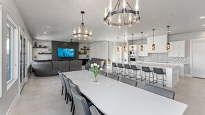 A modern kitchen with white cabinets, a central island with bar stools, and pendant lighting. - Sand Hollow Aquatic Adventure (Hurricane)