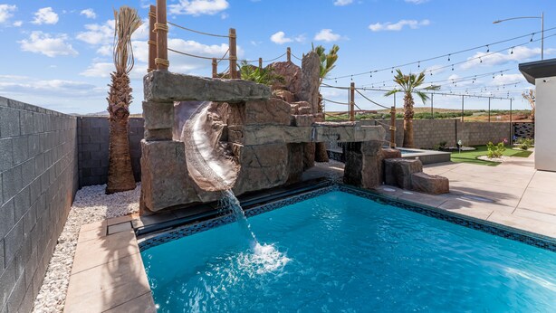 A swimming pool with a waterfall feature, surrounded by rocks and palm trees. - Sand Hollow Aquatic Adventure (Hurricane)