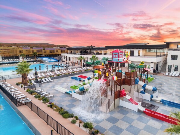 A resort pool area with a water slide and multiple lounge chairs.