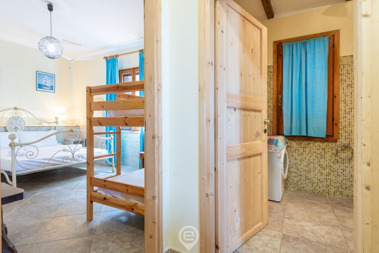A room with a bunk bed, a washing machine, and a tiled wall.