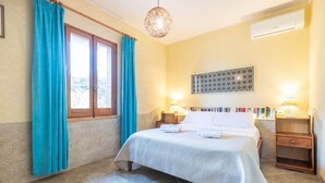 Une chambre à coucher comprenant un lit, des rideaux, une lampe fixée au mur, une table de chevet et un élément décoratif mural.