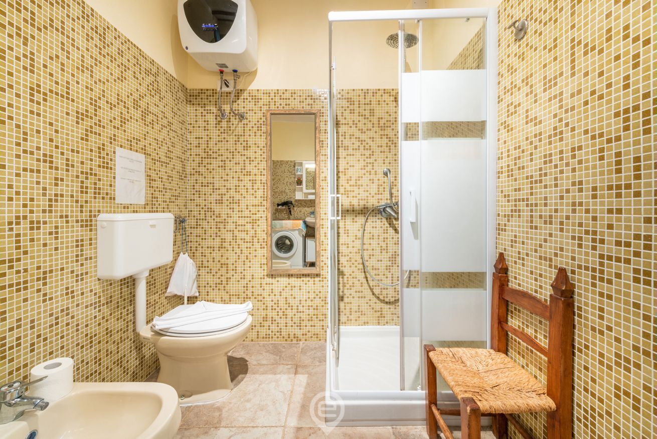 Un baño con inodoro, lavamanos y zona de ducha.