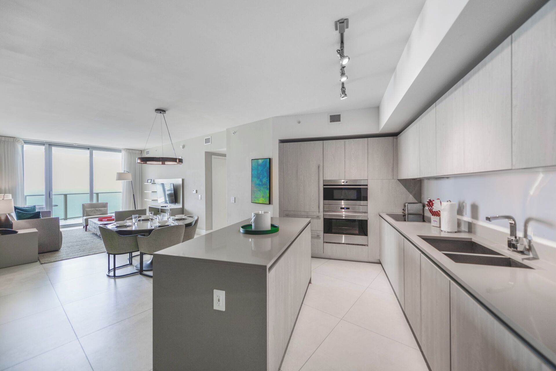 A modern kitchen with a central island, built-in appliances, and a dining area with a view.