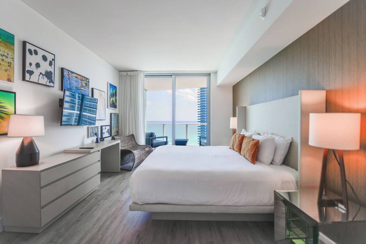 Een moderne hotelkamer met een groot bed, een bureau, een stoel en uitzicht op de stadshemel.