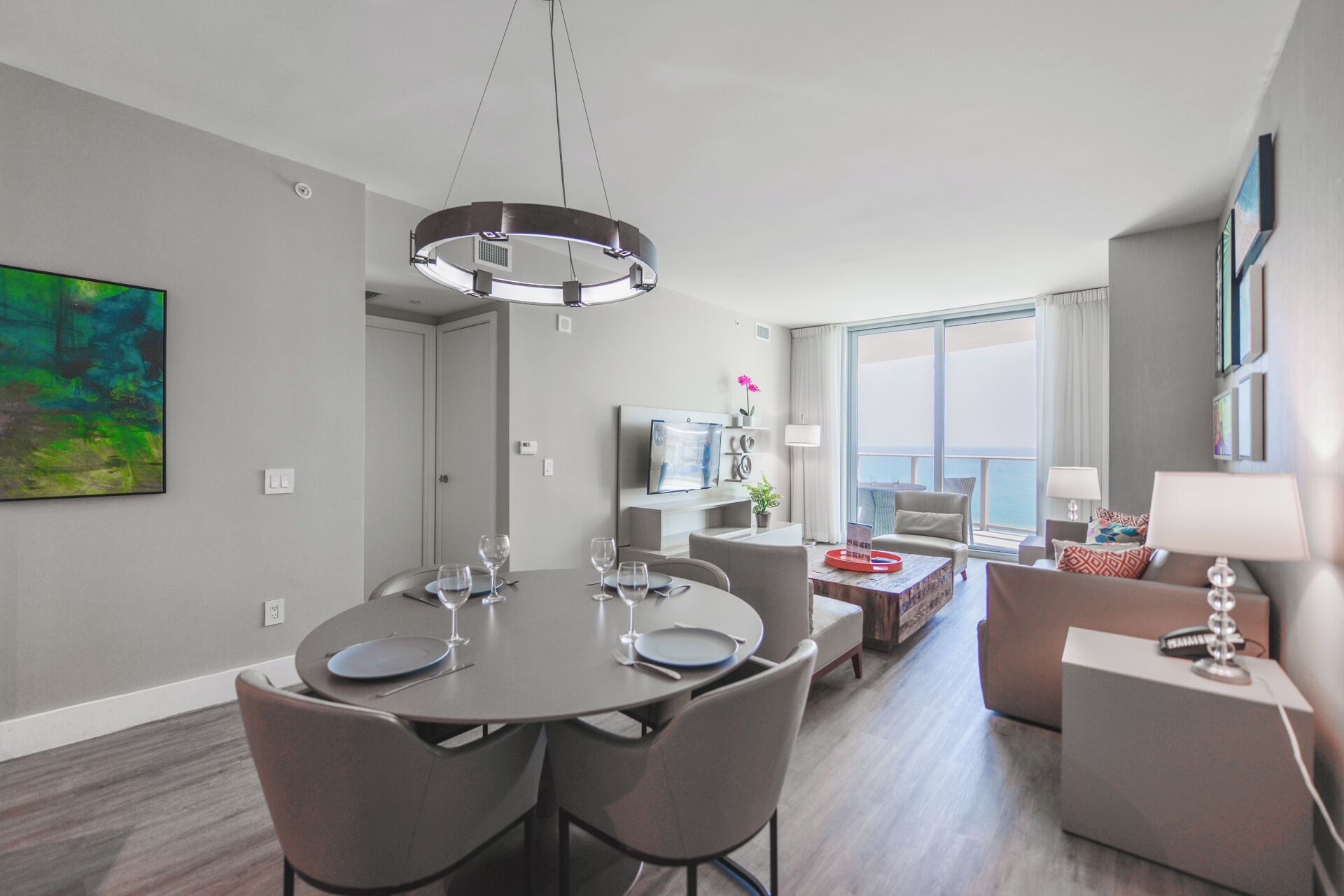 A modern hotel room with a dining area, a living area with a view, and a balcony.