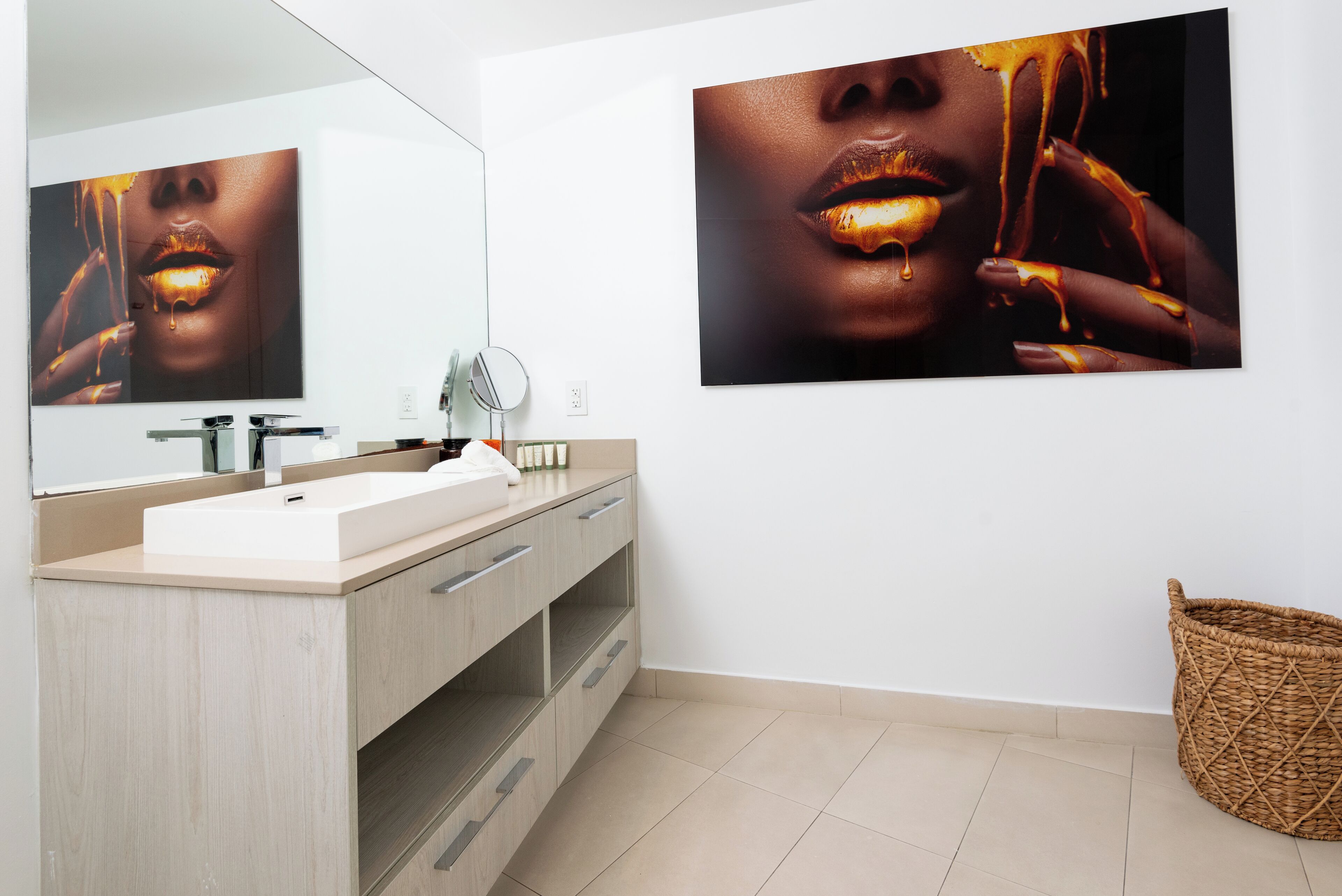 Ein modernes Badezimmer mit einem großen Spiegel, einem Waschbecken und zwei gerahmten Fotos an der Wand.