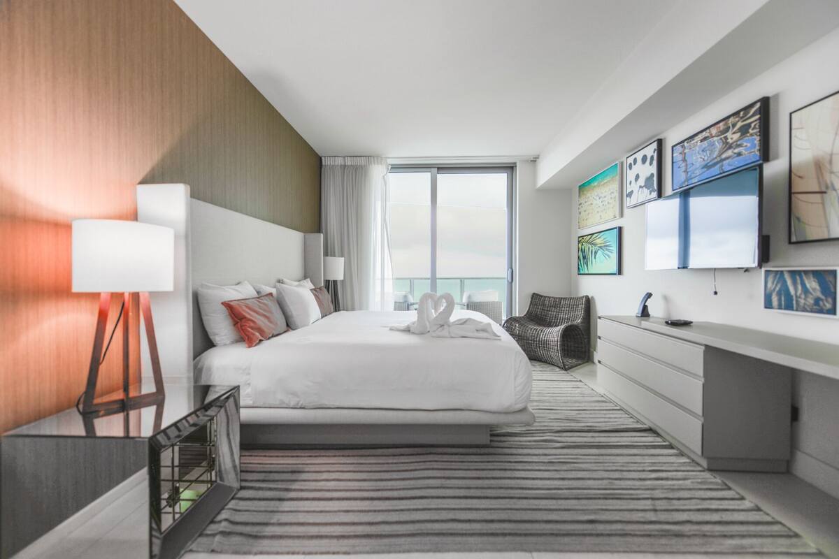 Een moderne hotelkamer met een groot bed, een bureau en uitzicht op de stad.
