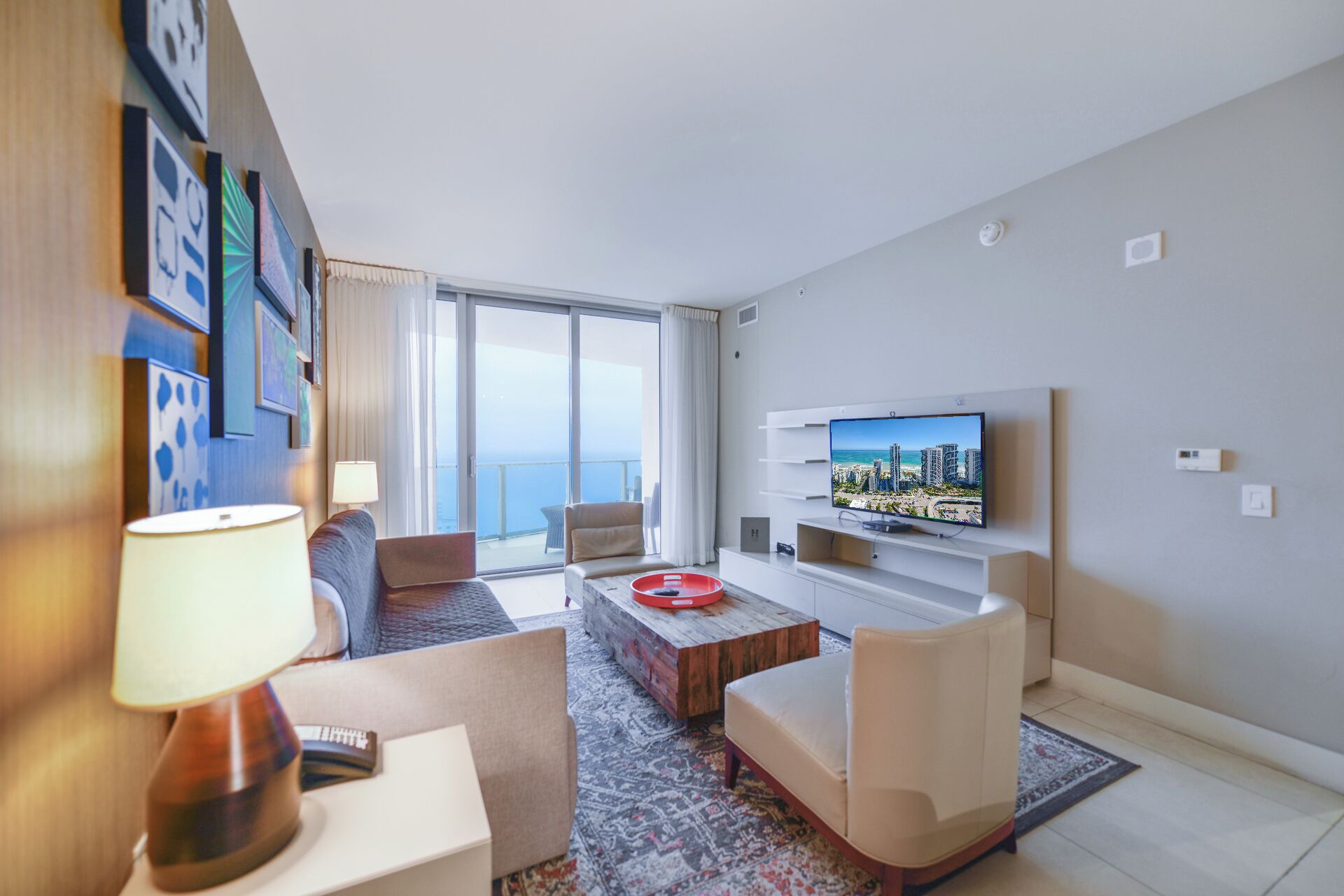 Quarto de hotel moderno com uma varanda ampla, televisão de tela plana e uma área de estar acolhedora.