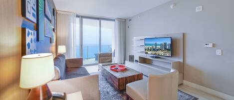 Quarto de hotel moderno com uma varanda ampla, televisão de tela plana e uma área de estar acolhedora.