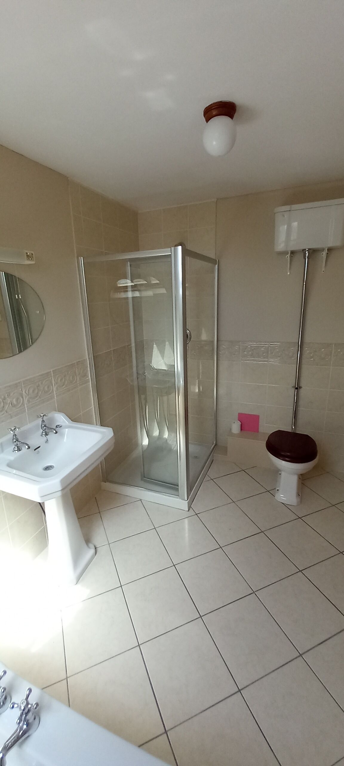 A bathroom with a glass-enclosed shower, a white sink, and a toilet.