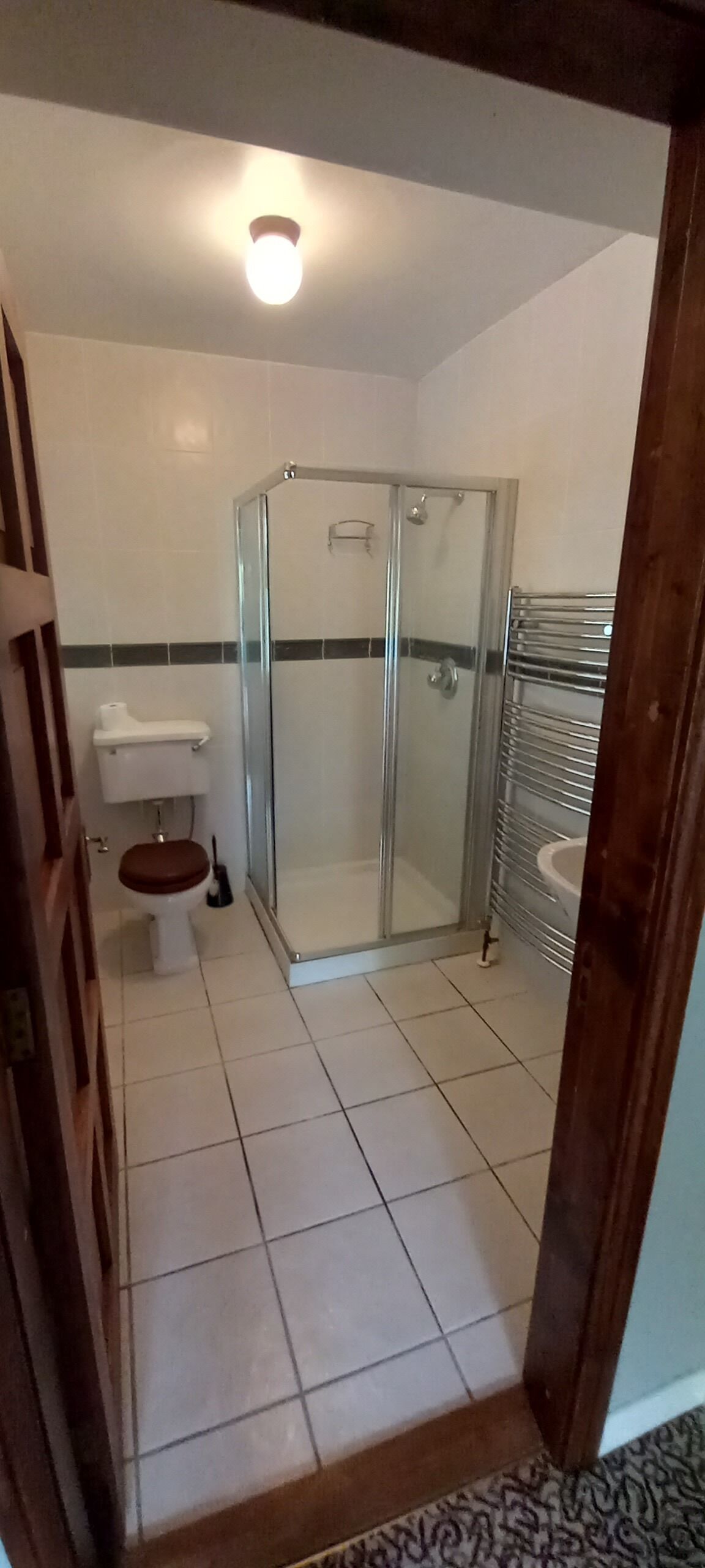 Un baño con inodoro, cabina de ducha y lavamanos.