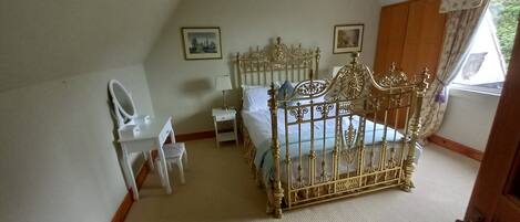 Een slaapkamer met een hemelbed, een nachtkastje, een stoel en een spiegel.