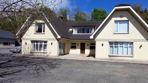 A two-story house with a sloped roof, large windows, and a driveway. - Ardsallagh Lodge (Tinnabinna)