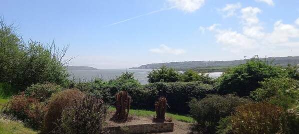A view of a coastal landscape with a stone pathway leading to a seating area.