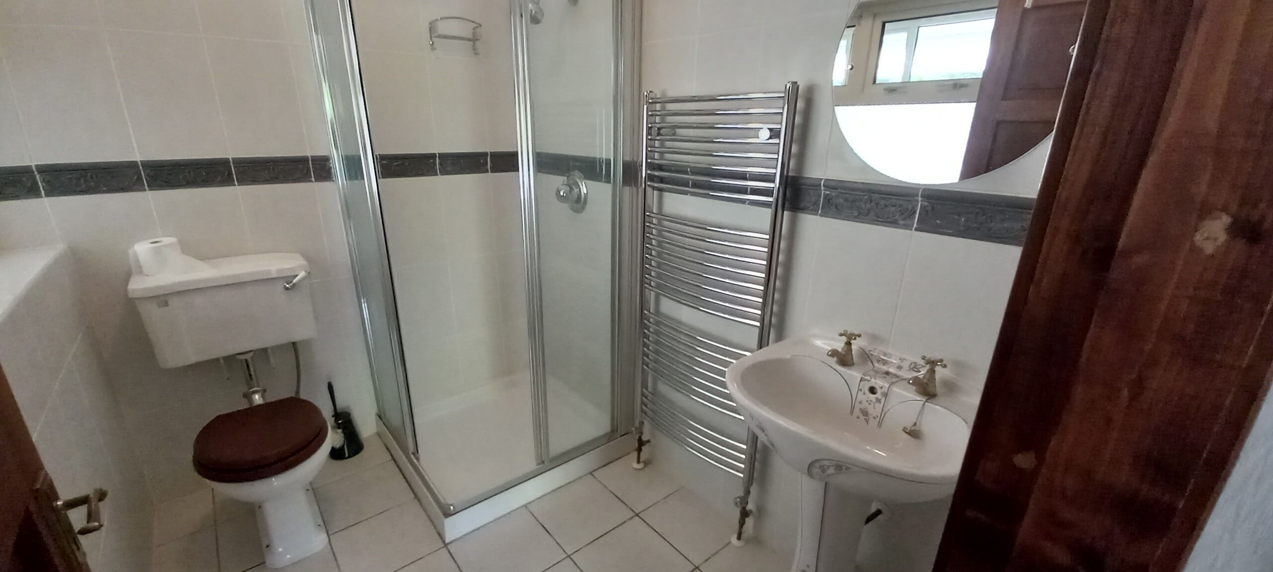A bathroom with a toilet, shower, and sink.