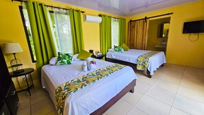 A hotel room with two beds, a TV, a lamp, and a window with curtains. - Confort Arenal (La Fortuna)