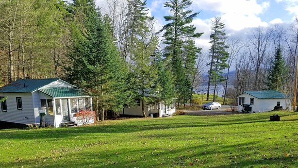 A row of cabins with a grassy field and trees in the background. - Cozy Cottage, Dog Friendly, Close to beach, Natural Wood, Waterfall on site (Barton)