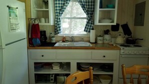 A compact kitchen with a sink, stove, and various kitchen items. - Cozy Cottage, Dog Friendly, Close to beach, Natural Wood, Waterfall on site (Barton)