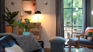 A cozy living room with a sofa, armchair, and a large window with curtains.
