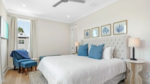 Ein Schlafzimmer mit einem großen Bett, einem Sessel und einem Deckenventilator.