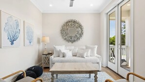 Ein modernes Wohnzimmer mit einem weißen Sofa, einem runden Spiegel und Kunstwerken an der Wand.
