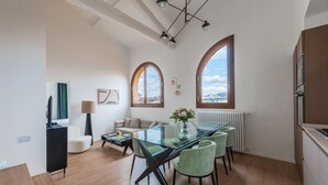 Un salon moderne avec une table à manger en verre, des chaises vertes, un canapé et une vue à travers des fenêtres en arc de cercle.