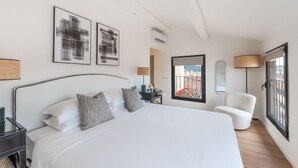 Une chambre à coucher moderne avec un grand lit, une chaise et des œuvres d’art accrochées aux murs.