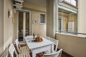 A balcony with a white table, chairs, and a wicker basket.