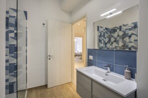 A modern bathroom with a large mirror, a sink, and a shower area.
