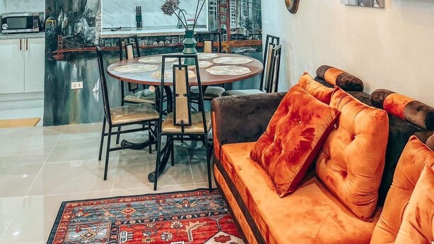 A modern living room with a round dining table, a sofa with orange cushions, and a chandelier. - Townhouse with a pool, arcade/gaming area and a massage chair! (City of Naga)
