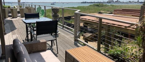 En terrass med utemöbler, ett bord och utsikt över havet.