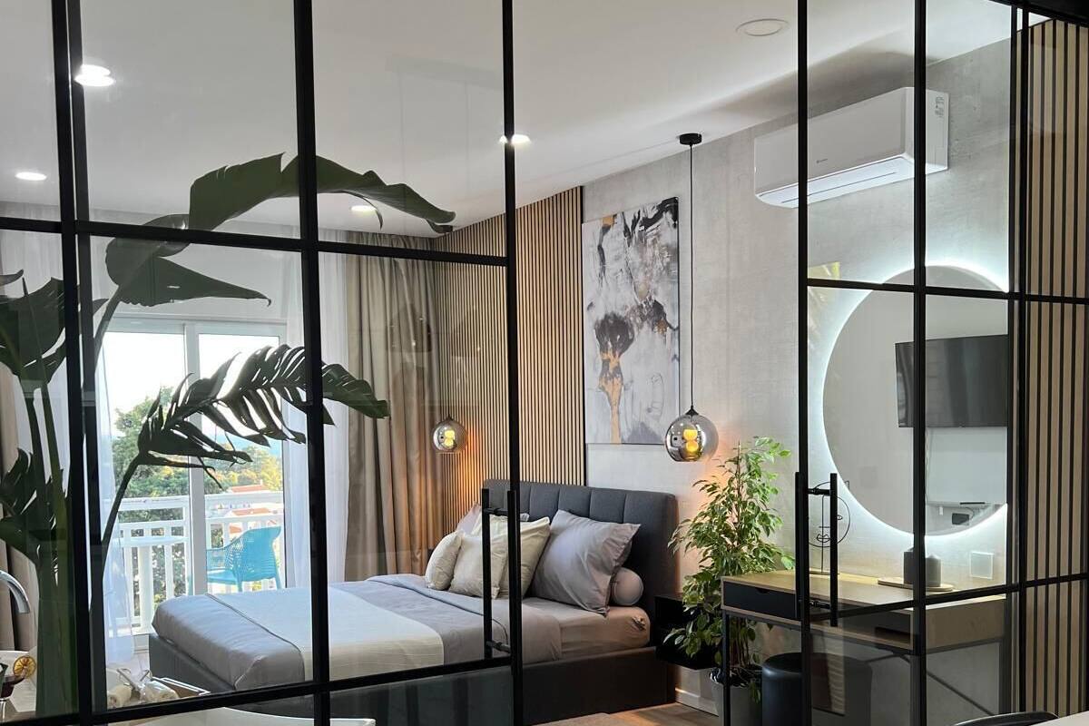 Un dormitorio moderno con cama, mesita de noche y un ventanal grande.