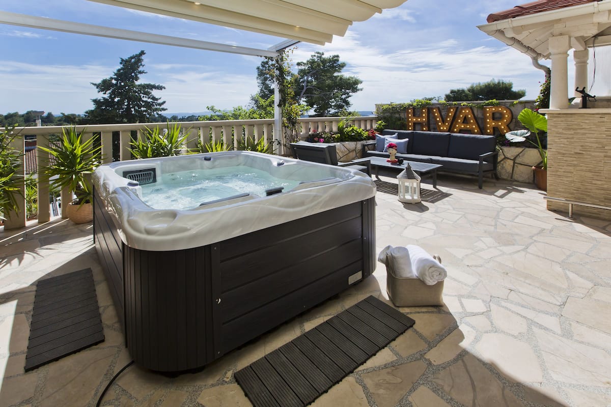 Jacuzzi en un patio con vistas, mobiliario exterior y una pérgola.