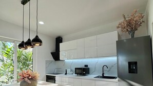 A modern kitchen with white cabinets, a marble countertop, a stainless steel refrigerator, and pendant lighting. - Casa Benita (Hvar)