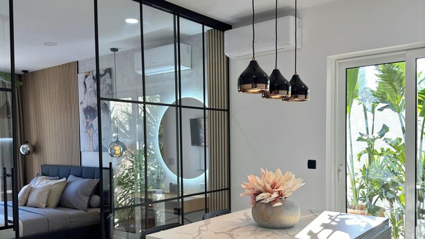 A modern living room with a glass partition, a marble island, and a view of greenery outside. - Casa Benita (Hvar)