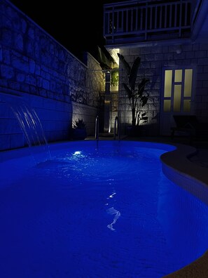A swimming pool with a stone wall and a small waterfall feature. - Casa Benita (Hvar)
