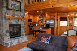 A cozy cabin interior with a stone fireplace, wooden furniture, a kitchen area, and a dining space. - Cozy Top of Mountain Cabin overlooking Meichtry Vineyards; 1.5hrs from Atlanta  (Talking Rock)