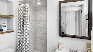 A bathroom with a shower, toilet, sink, and a mirror. - Charming 2 Bedroom Apartment Downtown In Vibrant Bozeman (Bozeman)