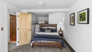 A bedroom with a bed, a nightstand, a lamp, and a door leading to a closet. - Charming 2 Bedroom Apartment Downtown In Vibrant Bozeman (Bozeman)