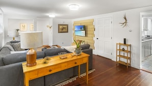 A modern living room with a grey sofa, wooden coffee table, and a TV mounted on a wooden wall. - Charming 2 Bedroom Apartment Downtown In Vibrant Bozeman (Bozeman)