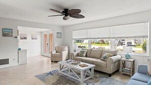A spacious living room with a white sofa, a coffee table, and a ceiling fan. - Waterfront Oasis, Pool, Dock, Location! (Cape Coral)